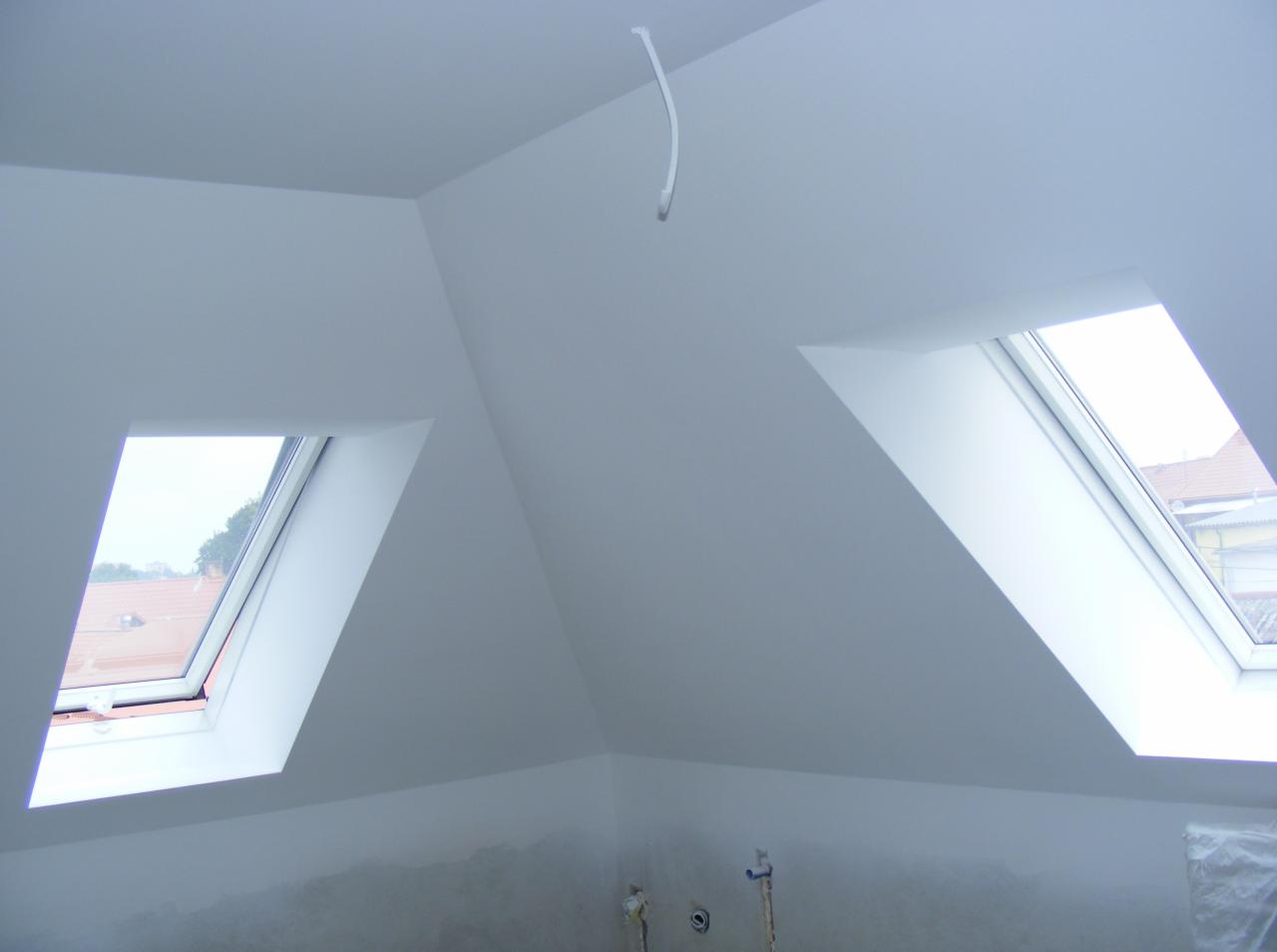 Poddasze po gładziowaniu i malowaniu na biało, widoczne dwa okna dachowe i wystający kabel ze ściany.