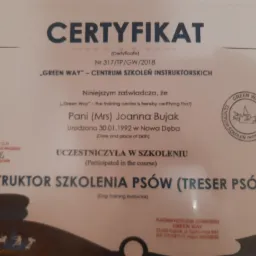 Certyfikat ukończenia szkolenia instruktora szkolenia psów, wydany przez 'Green Way' dla Joanny Bujak, z datą urodzenia i numerem certyfikatu, widoczne logo firmy.