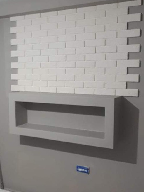 Ściana z dekoracyjnej białej cegły z szarą półką wnękową poniżej, na szarej ścianie, minimalistyczny design.