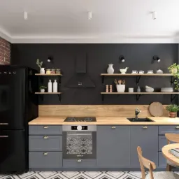 Nowoczesna kuchnia z ceglaną ścianą, czarnym sprzętem SMEG, szarymi szafkami i drewnianym blatem, uzupełniona otwartymi półkami z dekoracjami i geometryczną podłogą.