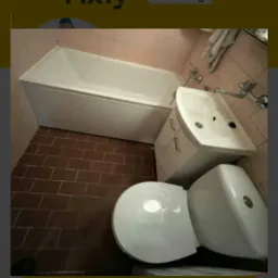 Łazienka po remoncie: biała wanna, umywalka z szafką i toaleta na tle różowych płytek i brązowej podłogi.