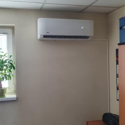 MG-Klima TABAKA Marek Giemza - Biały klimatyzator ścienny marki Vivax z wyświetlaczem ustawionym na 17 stopni, zainstalowany w biurze z kasetonowym sufitem, obok okna z zieloną rośliną doniczkową i szafy z kalendarzem.