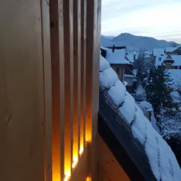 Drewniana balustrada balkonu z oświetleniem LED w zimowej scenerii górskiej miejscowości