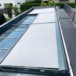 Przedsiębiorstwo Usługowo Handlowo Produkcyjne EUROL Małgorzata Czarnotta - Zewnętrzna, jasnoszara osłona przeciwsłoneczna zamontowana na szklanym dachu tarasu, widok z góry, nowoczesne budownictwo.