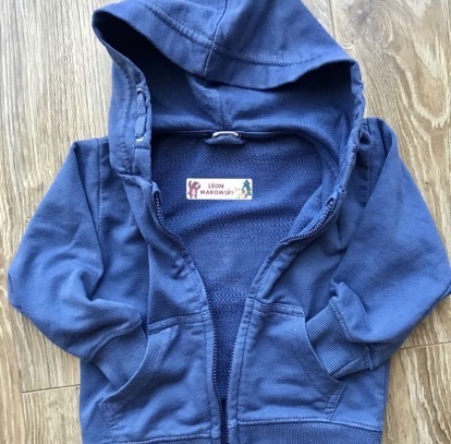 Niebieska rozpinana bluza z kapturem dla dziecka, z wszytą spersonalizowaną metką z imieniem i rysunkami zwierząt.