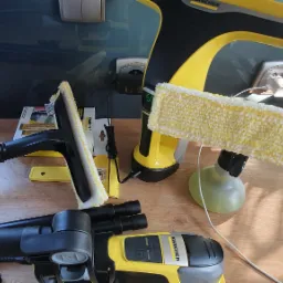 Zestaw do mycia okien marki Karcher z różnymi akcesoriami i dyszami na drewnianym blacie, widoczne pudełko i instrukcja obsługi.