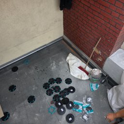 Paweł Porębski Natalia Kalczuk - Przygotowanie podłoża na balkonie: rozłożone podkładki dystansowe, narzędzia i materiały budowlane. Widok z góry na etap prac przed ułożeniem finalnej warstwy.