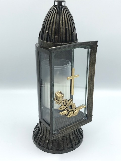 Znicz lampion z otwartymi drzwiczkami, zdobiony złotym krzyżem i różą, na białym tle.