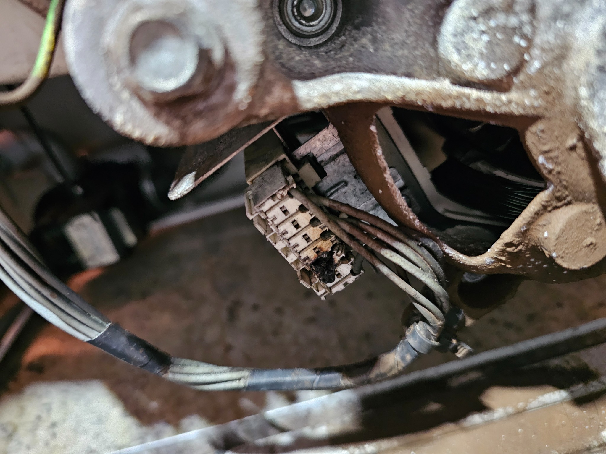 Uszkodzony, przypalony konektor elektryczny wewnątrz urządzenia AGD, z widocznymi przewodami i zabrudzeniami.