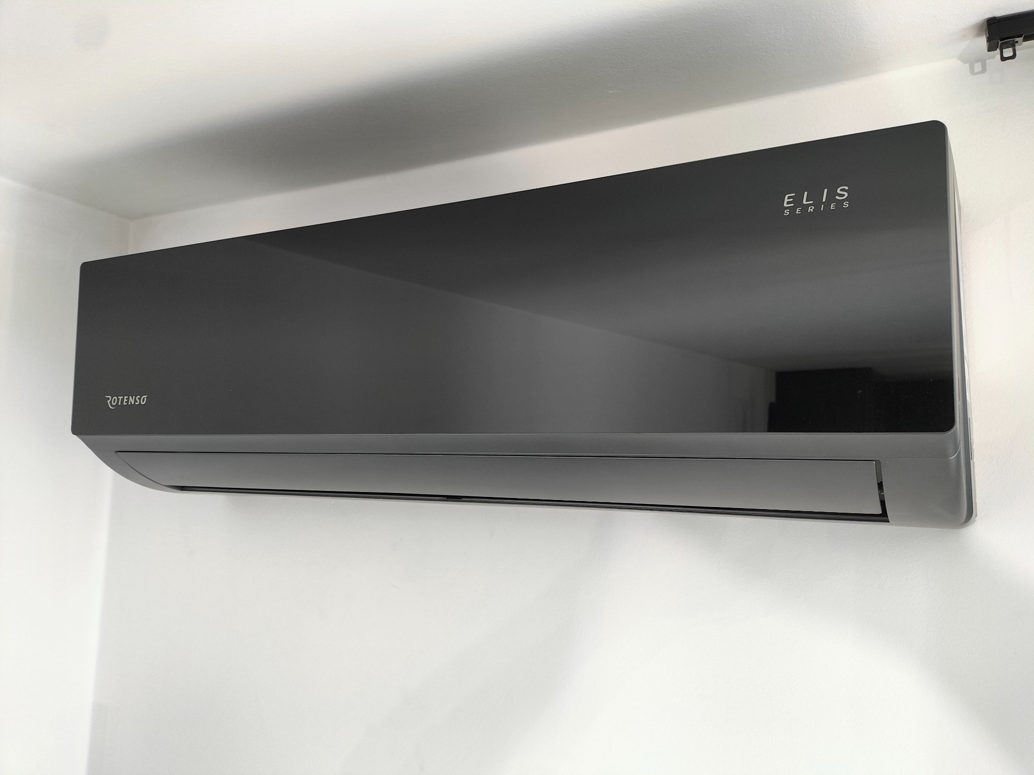 Czarny klimatyzator Rotenso Elis Series zamontowany na białej ścianie, widoczne logo i oznaczenie modelu.