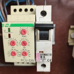 Bliski plan zamontowanego wyłącznika nadprądowego ETIMAT 10 B6 obok programowalnego przekaźnika czasowego PCU-520 z widocznymi przewodami elektrycznymi.