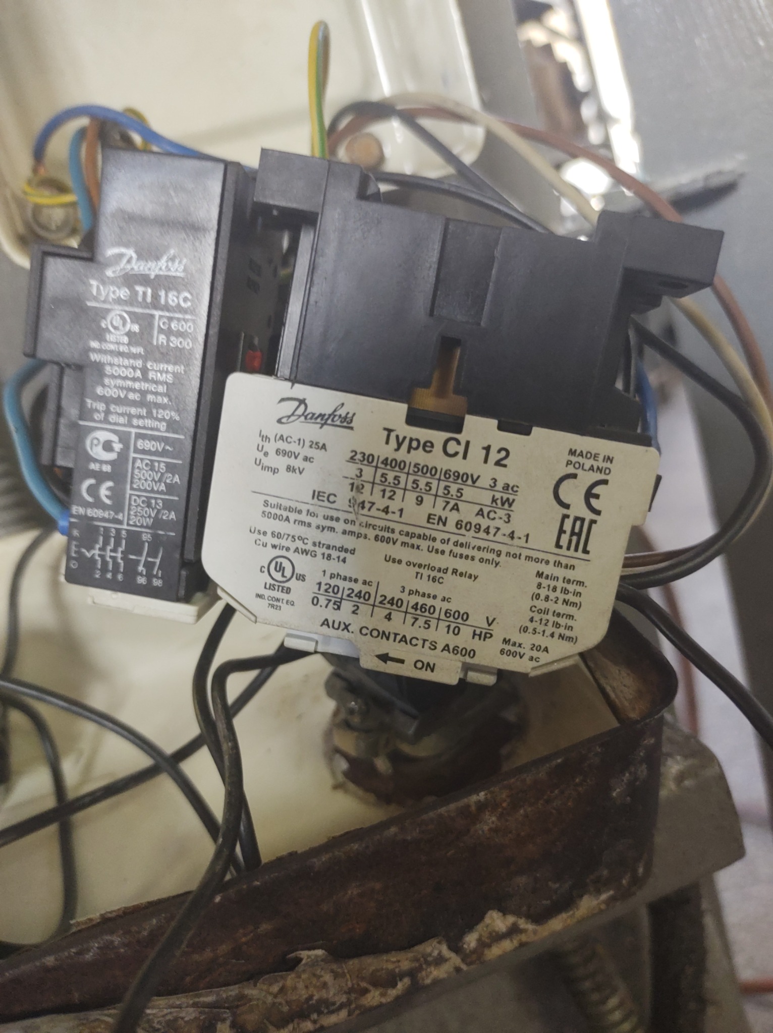 Styki elektryczne Danfoss Type TI 16C i CI 12, widoczne przewody, tabliczki znamionowe z parametrami technicznymi, osadzone na metalowej, skorodowanej podstawie.