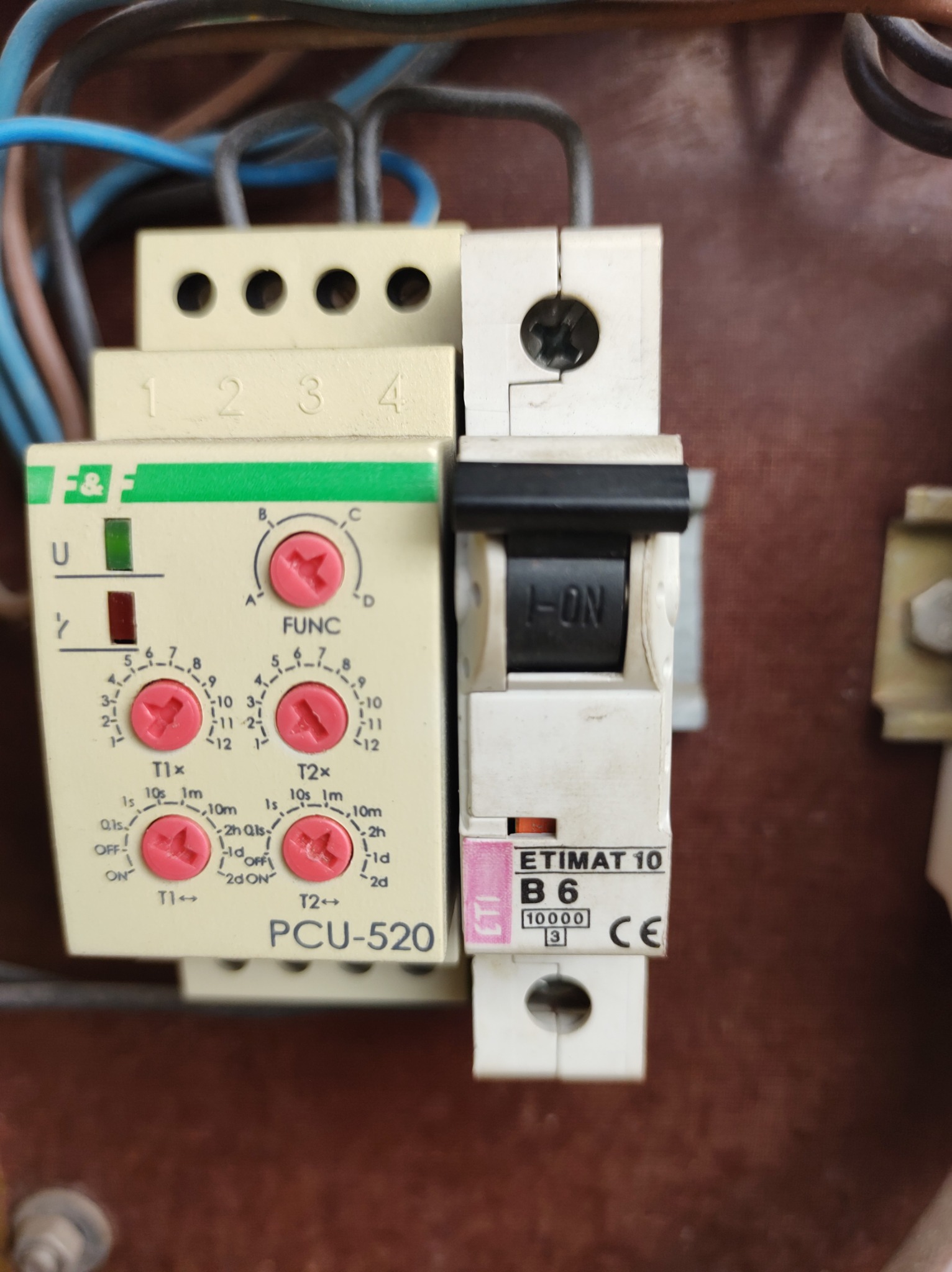 Bliski plan zamontowanego wyłącznika nadprądowego ETIMAT 10 B6 obok programowalnego przekaźnika czasowego PCU-520 z widocznymi przewodami elektrycznymi.