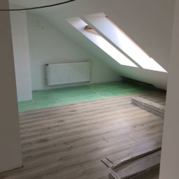 Gduli-Bud - Poddasze w trakcie układania paneli podłogowych Kronopol Room, widoczny fragment ocieplonej podłogi, okno dachowe i zakryty folią grzejnik.
