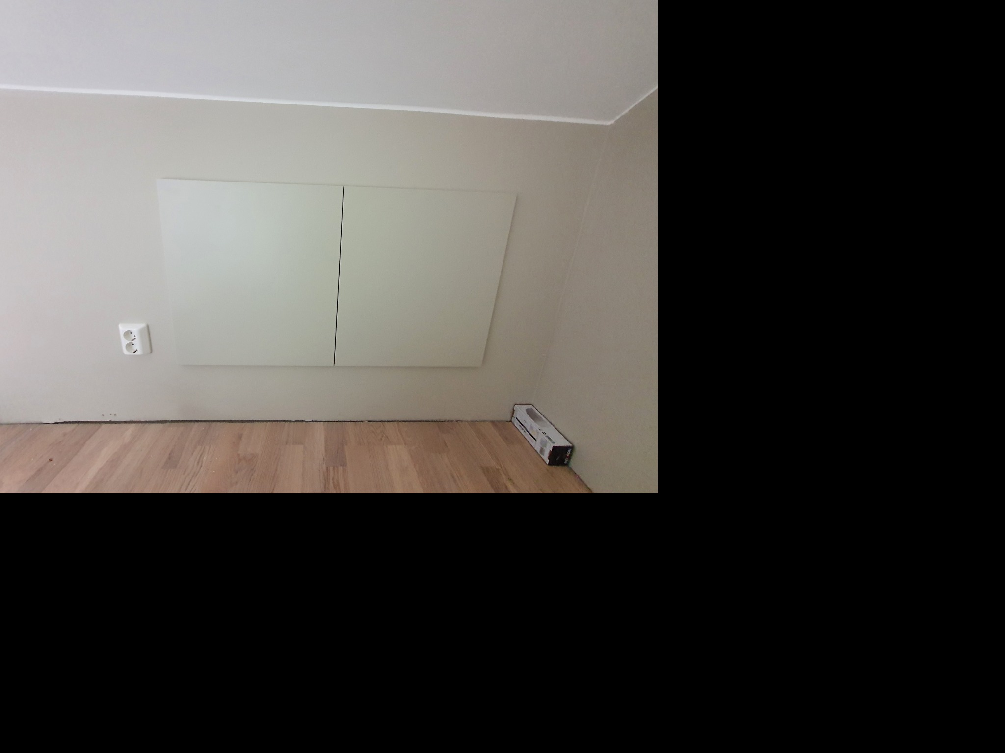 Świeżo położona podłoga z jasnych paneli, przy ścianie biała skrzynka rewizyjna i opakowanie paneli podłogowych.