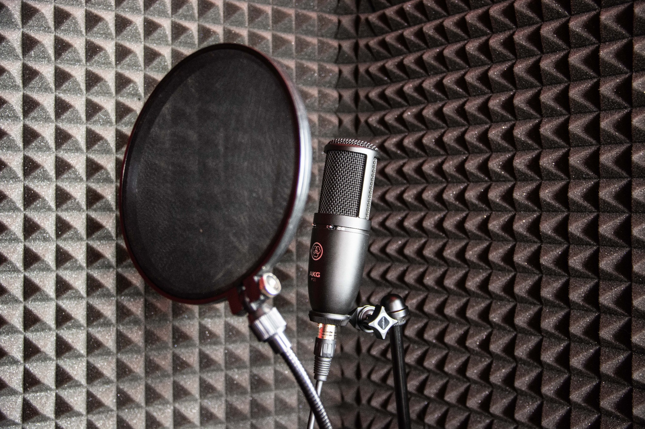 Mikrofon AKG P120 z pop filtrem w profesjonalnym studiu nagrań z panelami akustycznymi.