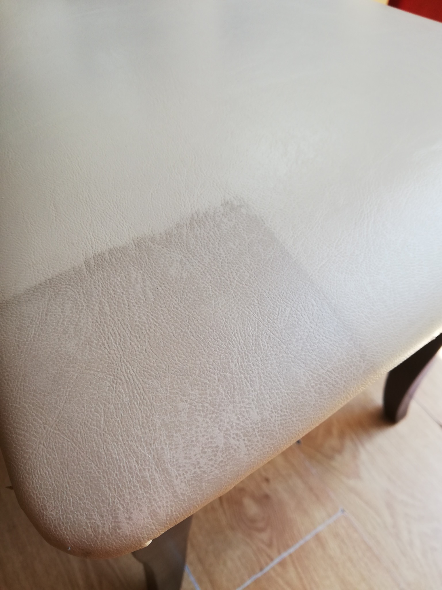 Fragment tapicerowanego krzesła z widoczną różnicą w czystości powierzchni po częściowym czyszczeniu.