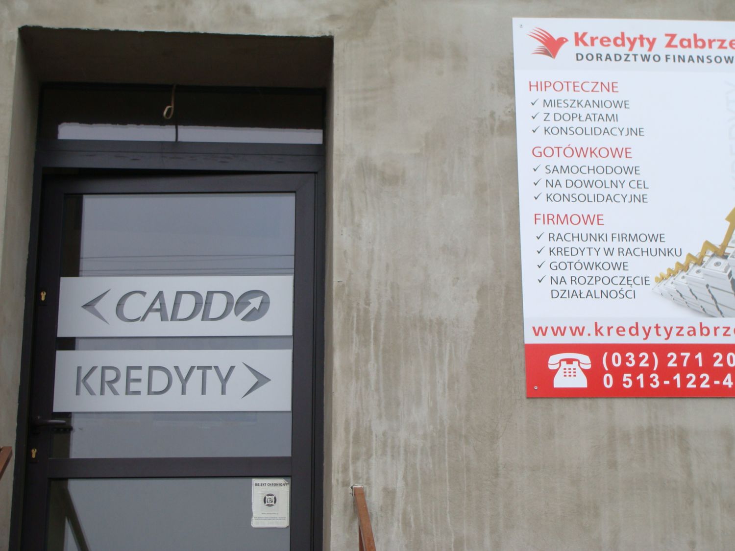 Wejście do biura kredytowego z szyldem 'CADDO KREDYTY' i tablicą informacyjną 'Kredyty Zabrze' z ofertą kredytów hipotecznych, gotówkowych i firmowych.