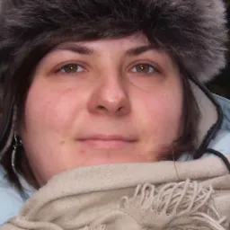 Portret kobiety w futrzanej czapce i szaliku, Wieliczka. Widoczne delikatne srebrne kolczyki i jasnoniebieska kurtka.