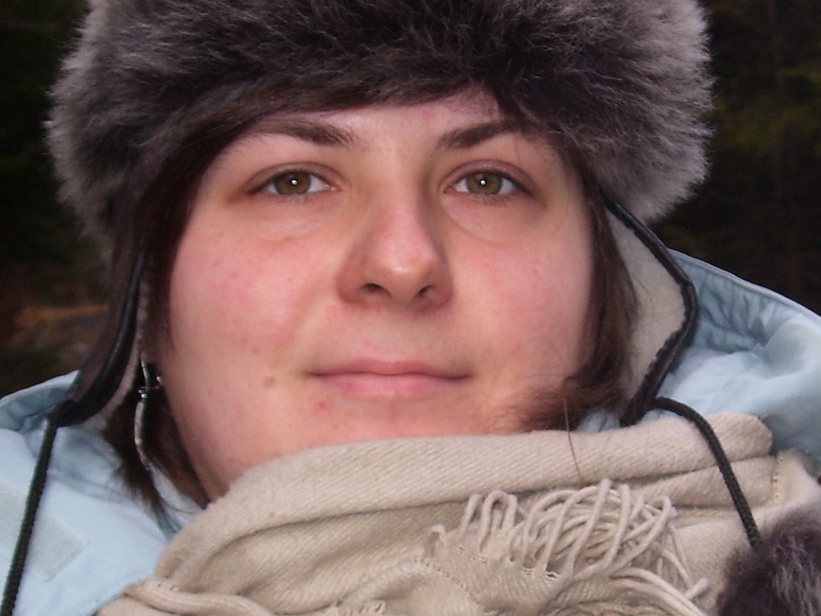 Portret kobiety w futrzanej czapce i szaliku, Wieliczka. Widoczne delikatne srebrne kolczyki i jasnoniebieska kurtka.