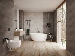 Nowoczesna łazienka: szare płytki ścienne, drewnopodobna podłoga, biała wanna wolnostojąca, minimalistyczna umywalka i duże okno z żaluzjami drewnianymi.