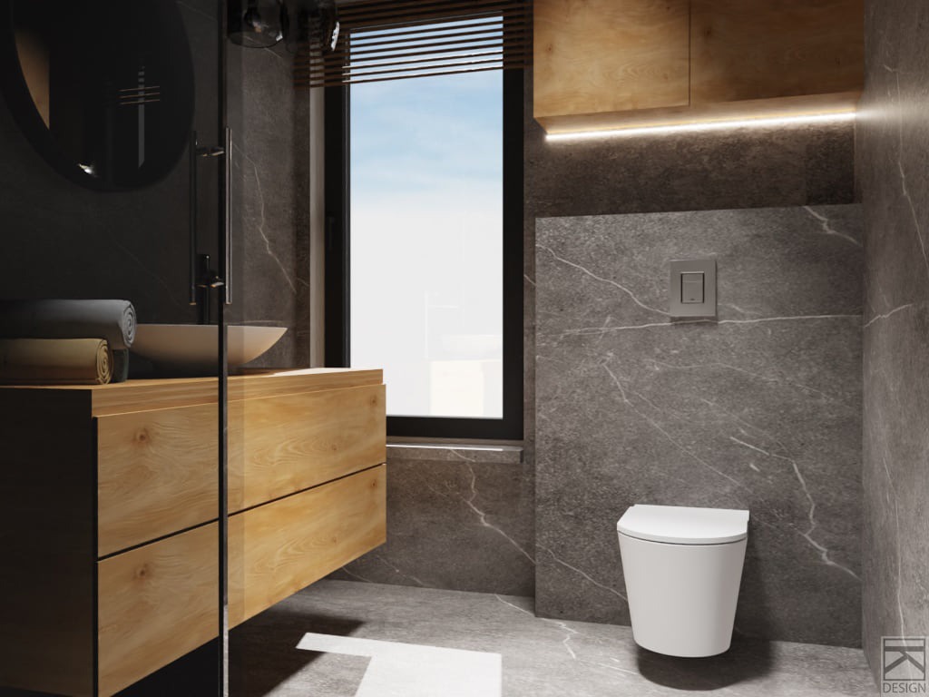 Nowoczesna łazienka w szarościach z drewnianą szafką pod umywalką, okrągłym lustrem i podwieszaną toaletą. Płytki imitujące kamień na ścianach i podłodze. Minimalistyczny design z akcentami czerni...