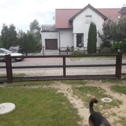 Alfa Welder - Zewnętrzna brama przesuwna z metalową siatką na posesji z widokiem na dom, samochody i fragment psiego ogona w trawie.