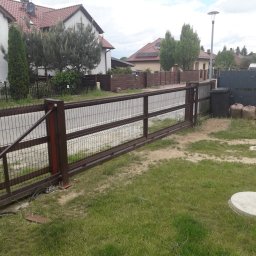 Alfa Welder - Przesuwna brama metalowa z siatkowym wypełnieniem, pomalowana na brązowo, zamontowana przed domem jednorodzinnym z widocznym trawnikiem i ulicą w tle.