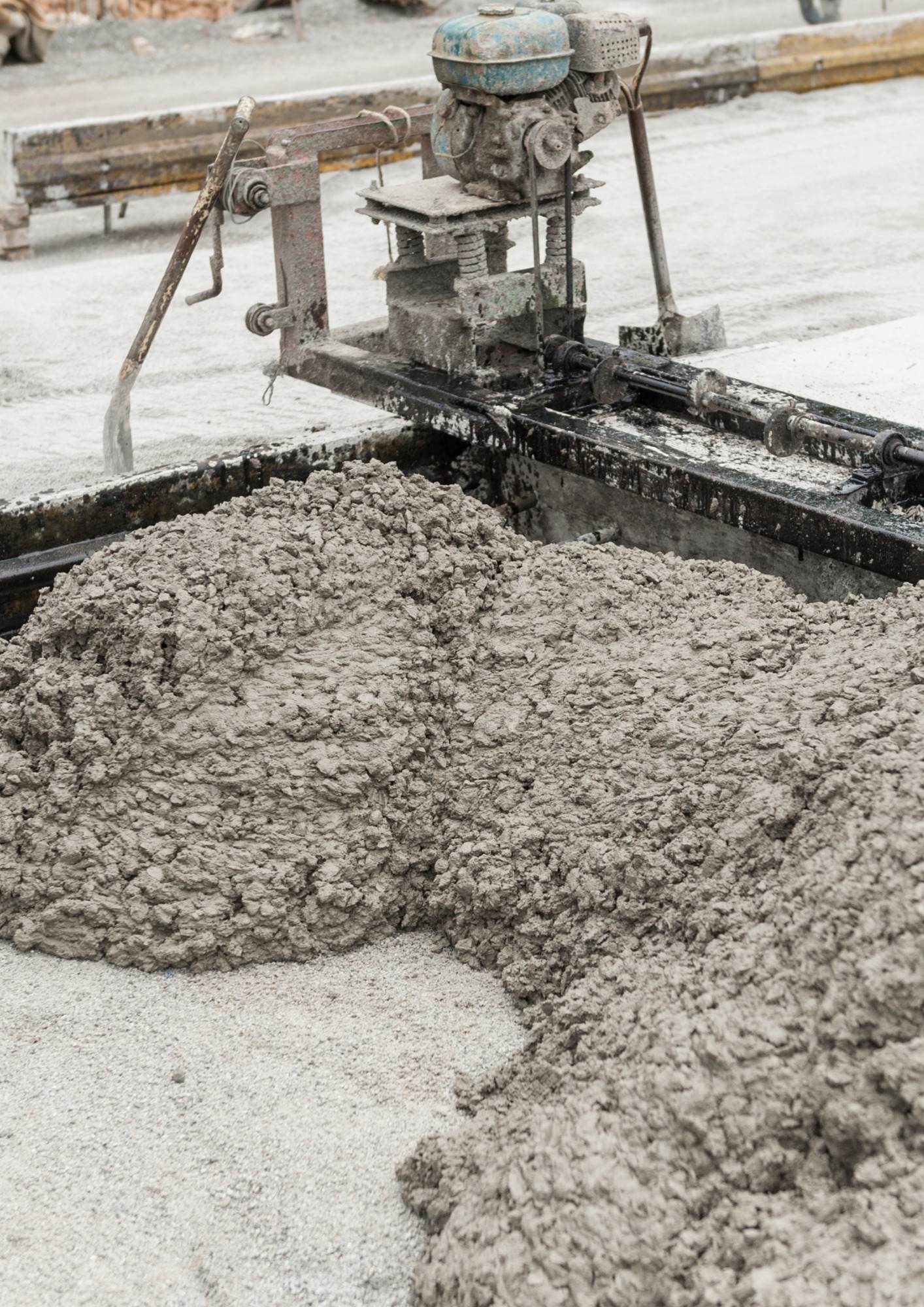 Świeżo wylany, gęsty beton z widoczną maszyną do rozprowadzania, ukazującą teksturę i proces wylewania.