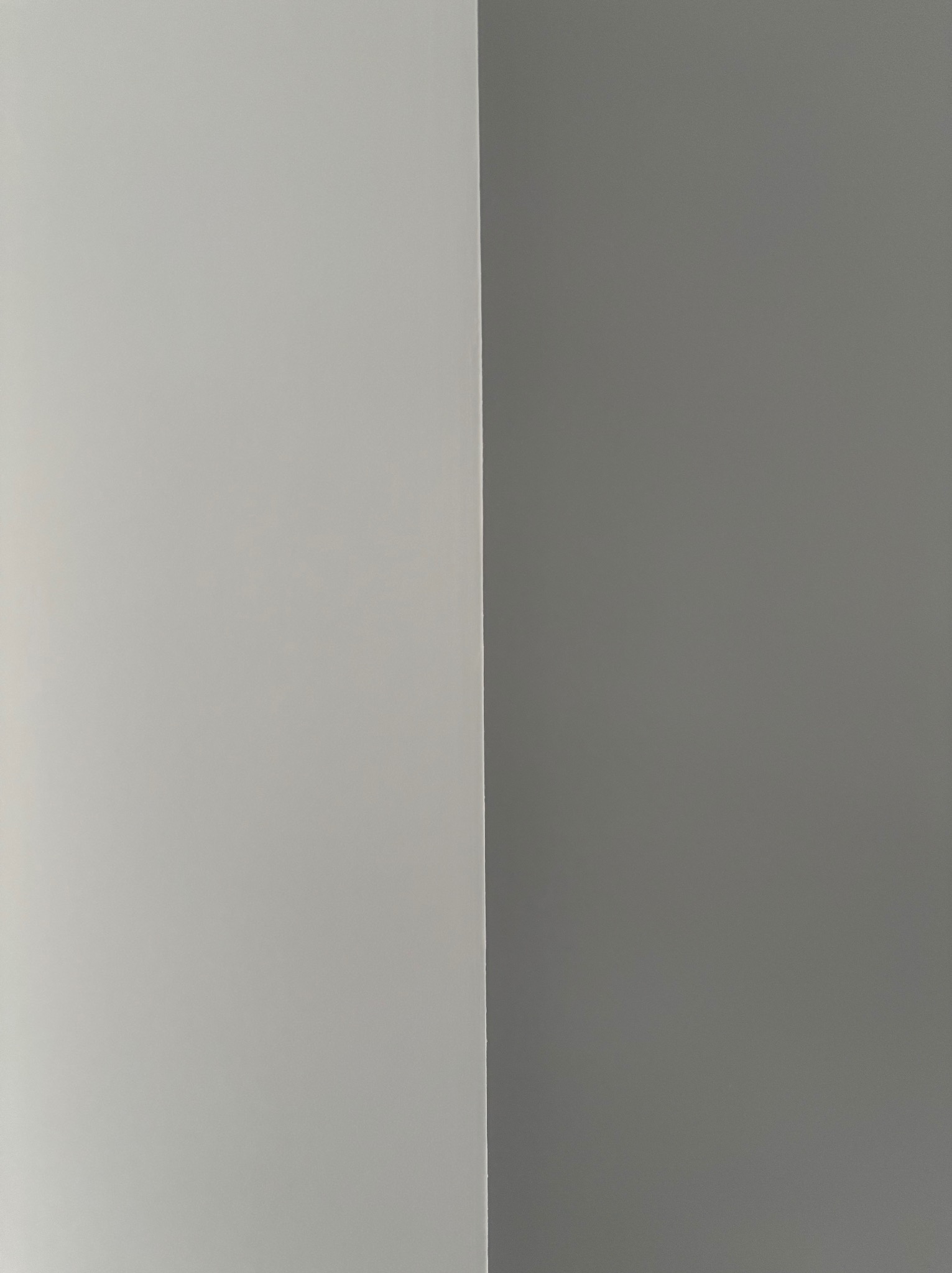 Ściana pomalowana na dwa odcienie szarości, z wyraźnym podziałem kolorów w rogu, ukazująca precyzję wykonania malowania.