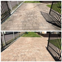 MISJA OCZYSZCZANIE - Efekt czyszczenia kostki brukowej: porównanie stanu przed (szara, zabrudzona) i po (czysta, brązowa) zabiegu. Widok z góry, brama i zieleń w tle.