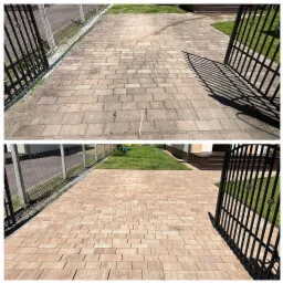 Efekt czyszczenia kostki brukowej: porównanie stanu przed (szara, zabrudzona) i po (czysta, brązowa) zabiegu. Widok z góry, brama i zieleń w tle.