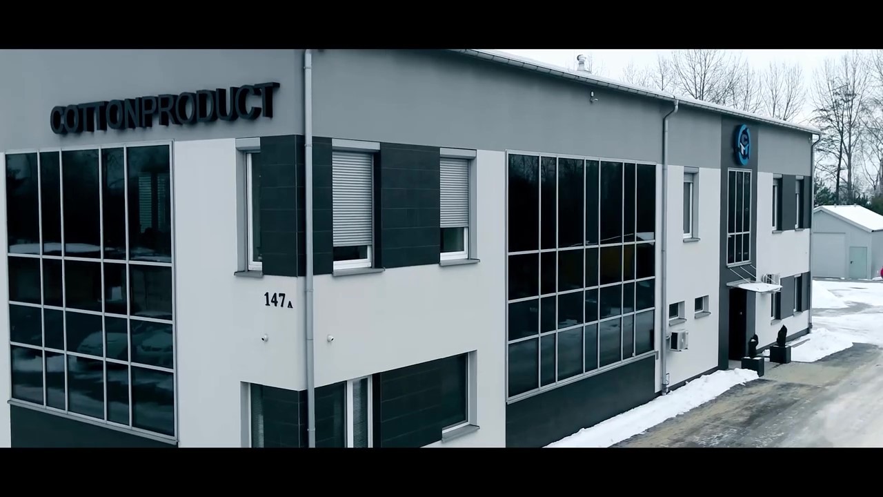 Budynek firmy Cotton Product z dużymi oknami i numerem 147A, widoczny w zimowej scenerii.
