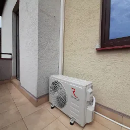 Zewnętrzna jednostka klimatyzacji Rotenso zamontowana na balkonie w Jabłonnie, widok z boku, z fragmentem elewacji i okna.