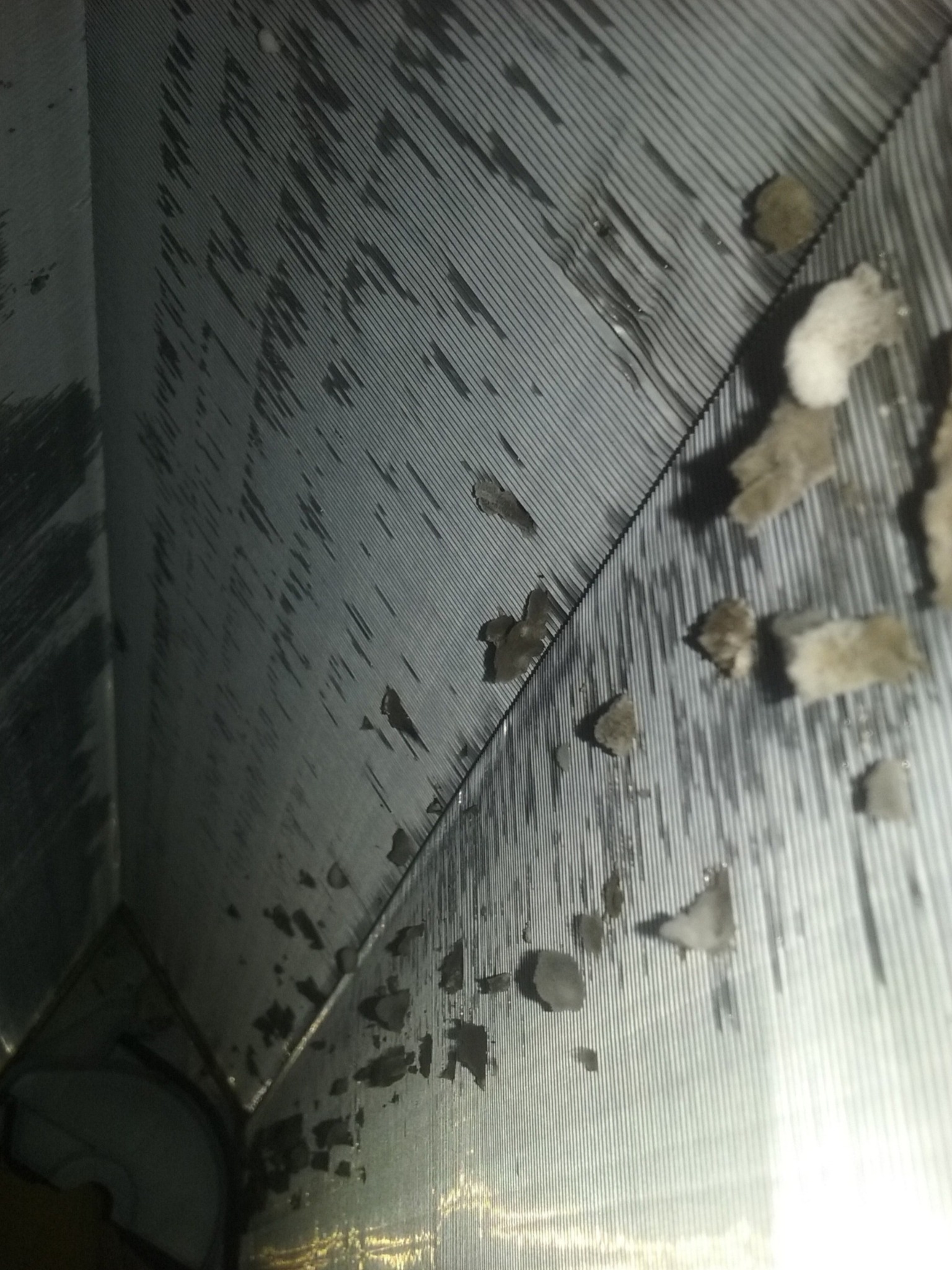 Wnętrze kanału wentylacyjnego z widocznymi zabrudzeniami i kurzem, oświetlone od dołu, ukazujące potrzebę czyszczenia i konserwacji.