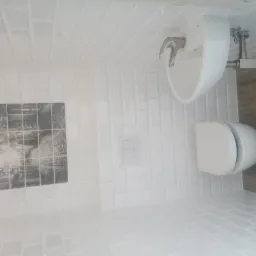 Nowoczesna łazienka z białą armaturą i płytkami typu metro, uzupełniona czarno-białą grafiką na ścianie.