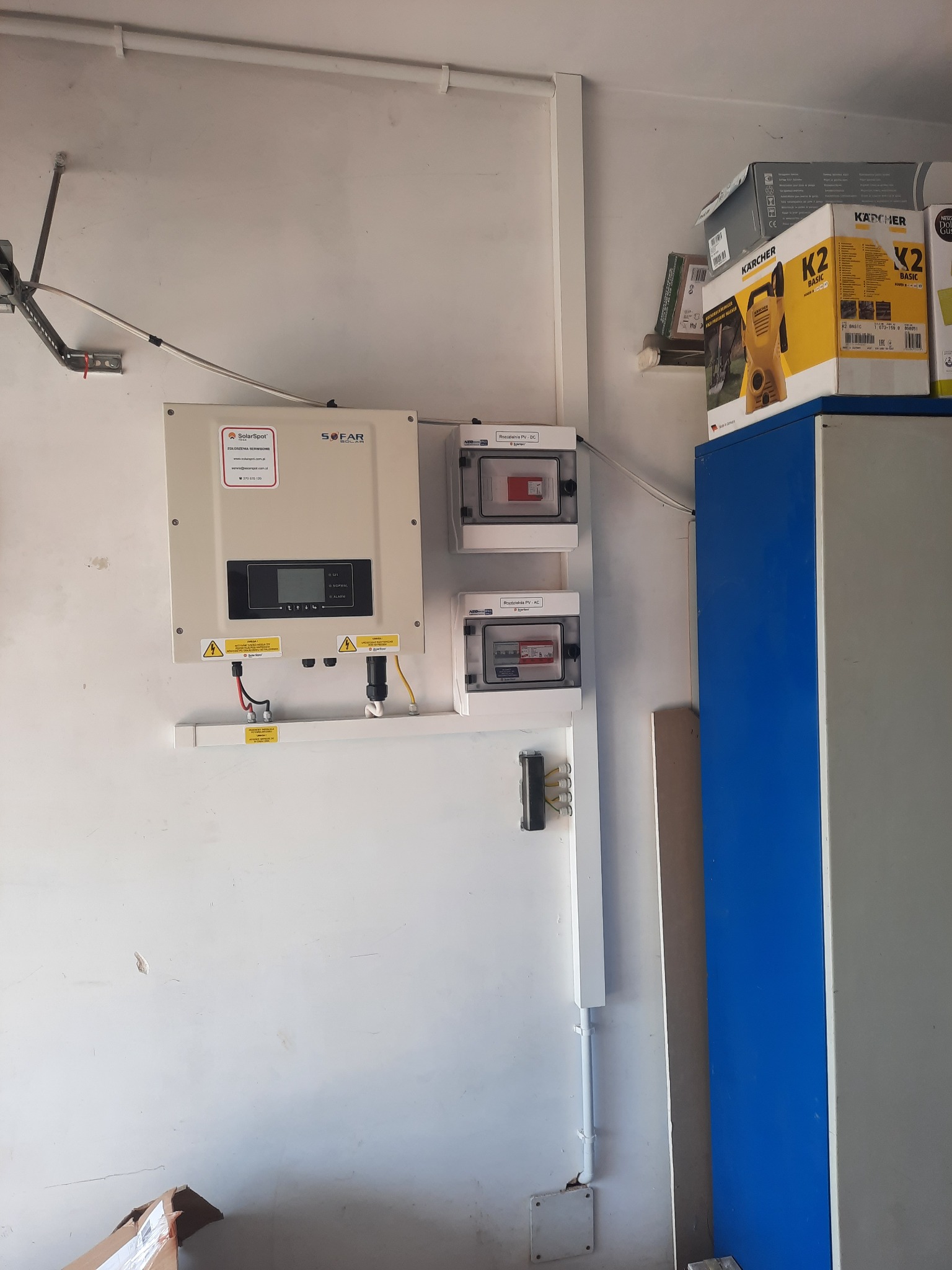 Zamontowany inwerter fotowoltaiczny SOFAR z rozdzielnicami PV-DC i PV-AC na białej ścianie wewnątrz budynku, widoczne kable i oznaczenia ostrzegawcze.