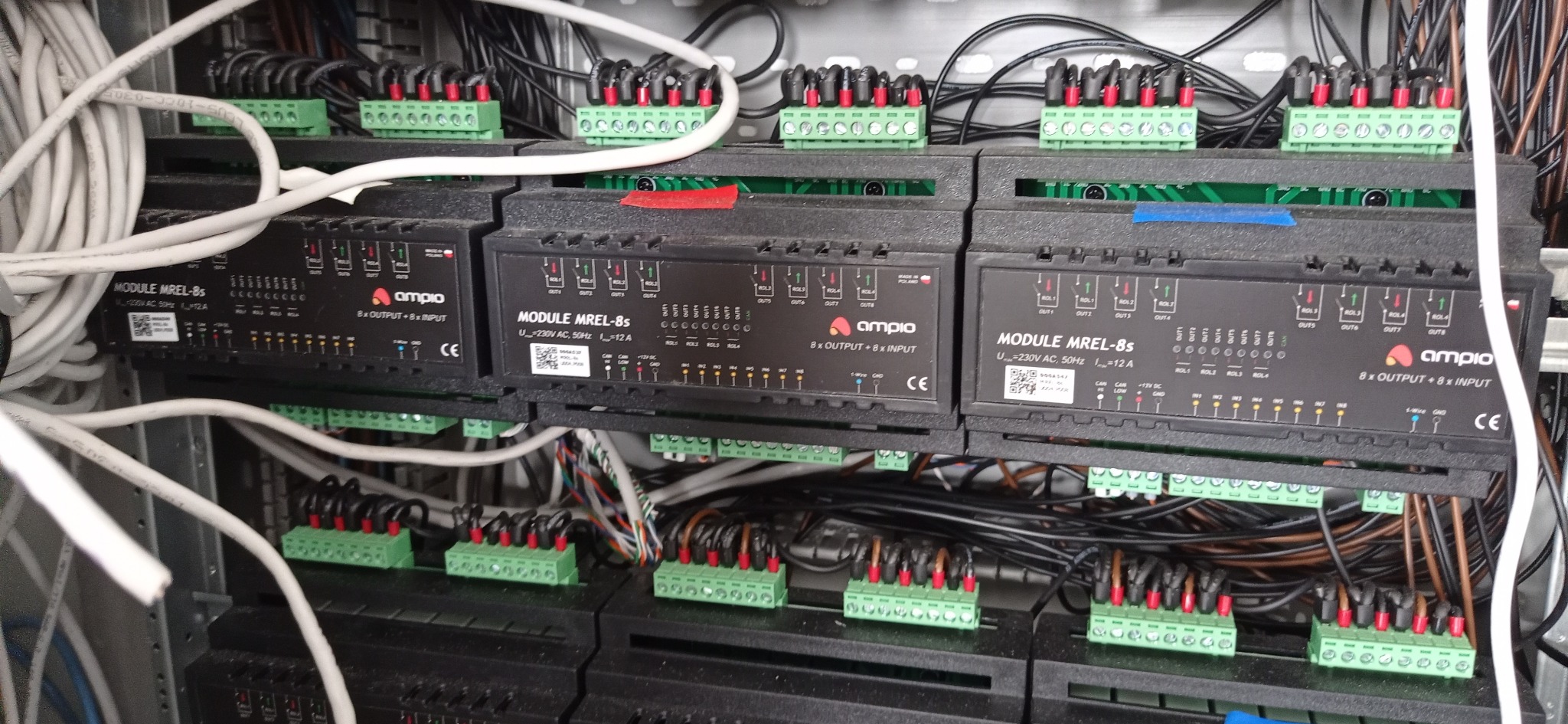 Rozdzielnica elektryczna z modułami sterującymi Ampio MREL-8s, widoczne liczne przewody i złączki, instalacja w trakcie montażu.