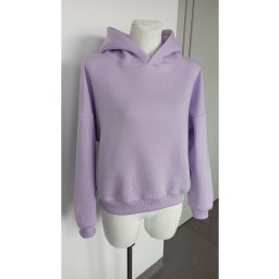 Liliowa bluza z kapturem, uszyta z miękkiej dzianiny, prezentowana na białym manekinie na tle białej ściany.