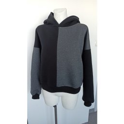 Dwukolorowa bluza z kapturem, czarno-szara, na manekinie bez głowy, z wyraźnym podziałem kolorystycznym na połowy.