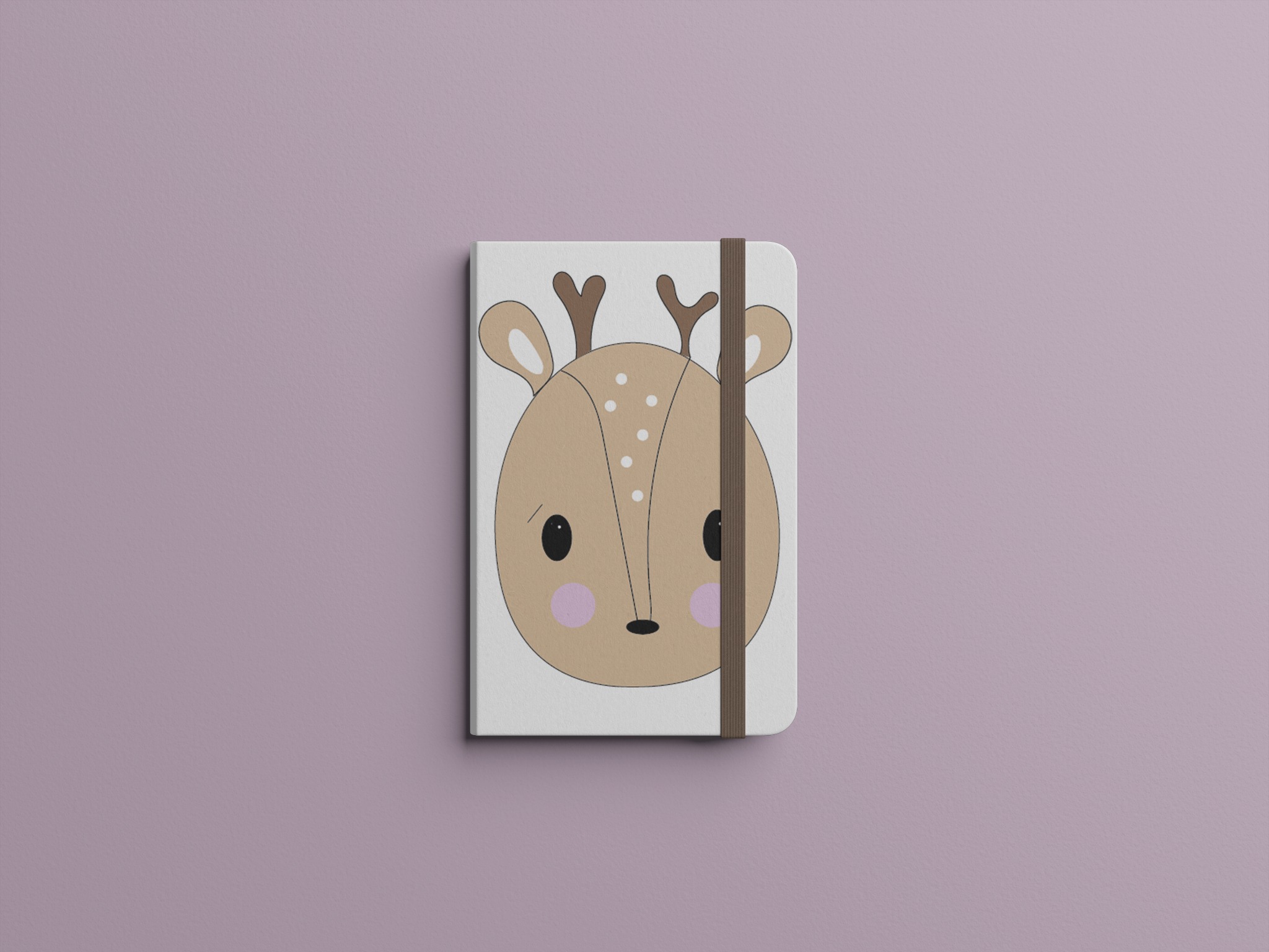 Zamknięty notatnik z ilustracją głowy jelenia w stylu cartoon na okładce, zabezpieczony brązową gumką na fioletowym tle.