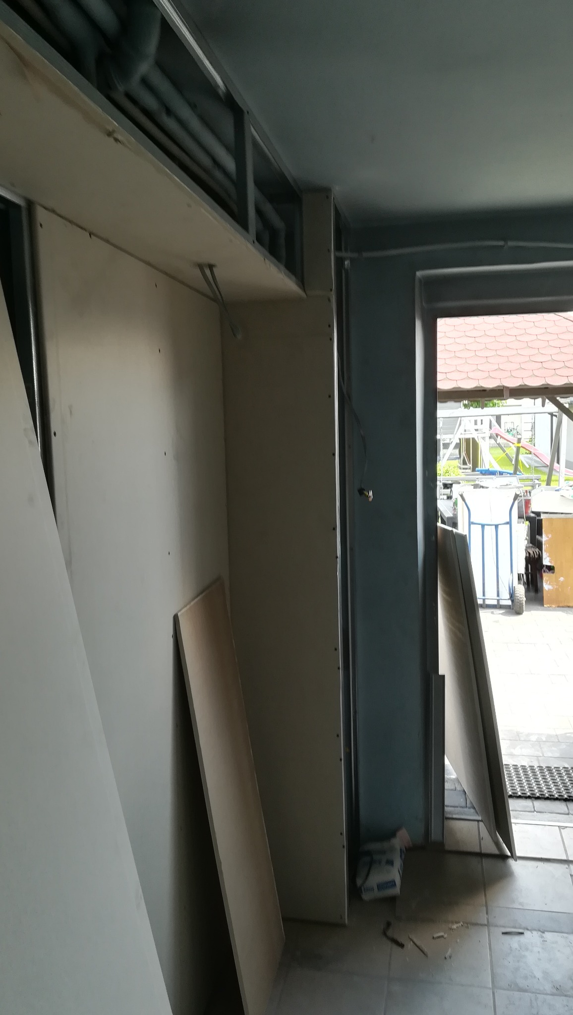 Montaż szkieletu sufitu podwieszanego i ścianki działowej z profili metalowych oraz płyt gipsowo-kartonowych w trakcie prac wykończeniowych, widoczne przewody instalacji.