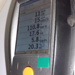 Analizator spalin Testo 330-1 LL pokazuje pomiary CO, CO2, temperatury i O2. Wyświetlacz z czytelnymi danymi, trzy żółte przyciski funkcyjne i zielona naklejka na obudowie.