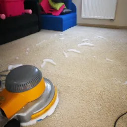 Czyszczenie jasnego dywanu w pokoju dziecięcym za pomocą szorowarki z pianą czyszczącą, w tle widoczne meble i grzejnik.