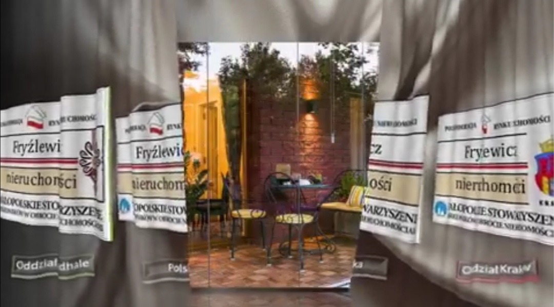 Umeblowany taras z ceglaną ścianą i oświetleniem, widoczny przez banery reklamowe agencji nieruchomości Fryźlewicz.