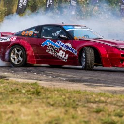 FotoPatrykBierski - Czerwony samochód do driftu, z numerem 610, bokiem na asfalcie, spod kół unosi się dym, widoczne logo KONDREX i MIC.EU Performance.