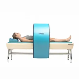 Kobieta leżąca na leżance podczas zabiegu z użyciem urządzenia terapeutycznego z niebieską obręczą.