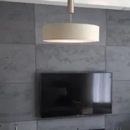 Ściana wykończona szarymi panelami imitującymi beton, z widocznym telewizorem i lampą sufitową w kształcie cylindra.