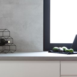 StudioRR MONIKA ROGOZIK-ROMANOWSKA - Nowoczesna kuchnia: butelka wina w metalowym stojaku, awokado, limonki i noże na tle szarej ściany i białych szafek.