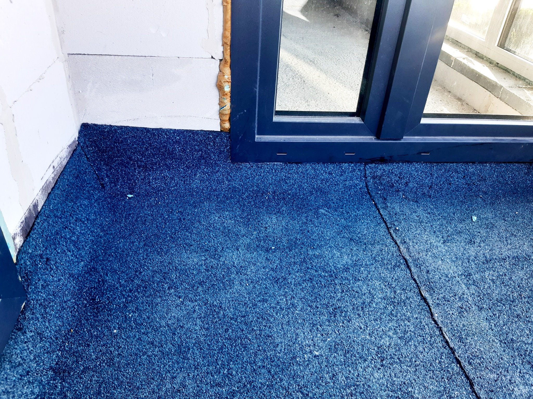 Detale izolacji dachu płaskiego w Bielsko-Białej z widocznym oknem dachowym i pianką uszczelniającą przy ścianie.